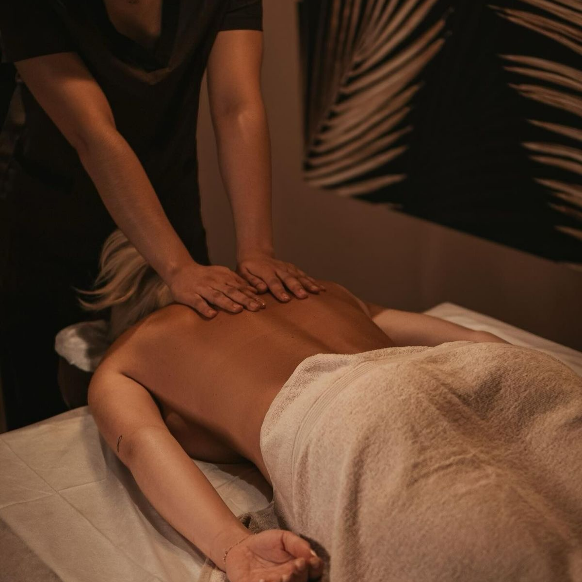Person receiving a massage in a dimly lit room.sleAura Spa & Wellness offers professional massage therapy, facials, pedicures, waxing, nails, brows, lashes, and beauty treatments in Valsayn and Marabella, creating a relaxing luxury spa experience in Trinidad.
