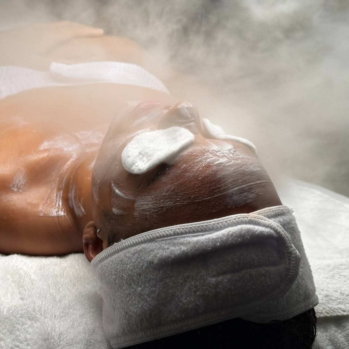 Person receiving a steam facial treatment with steam rising from the face.Modern Caribbean home and body products by IsleAura designed to elevate everyday wellness through premium fragrances, nourishing body care, and calming rituals.